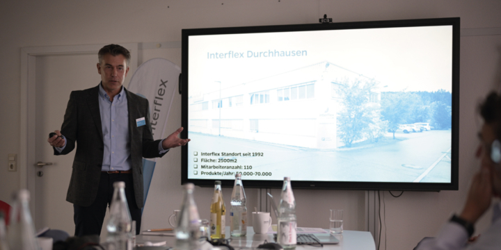 Interflex-Mitarbeiter steht vor Leinwand und hält Unternehmenspräsentation