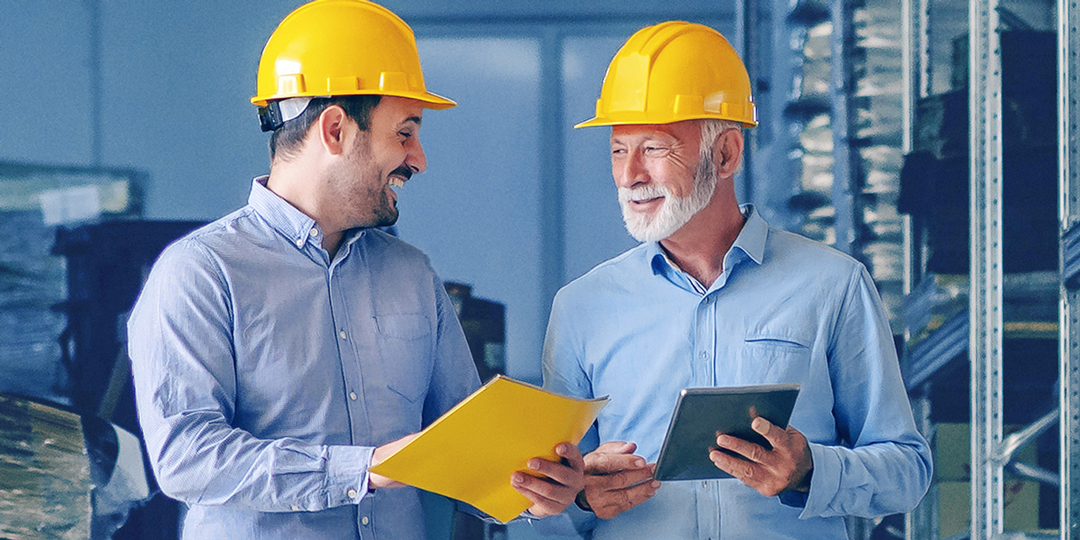 Zwei Männer mit Schutzhelm unterhalten sich lächelnd über das Modul Kostenmanagement von Interflex