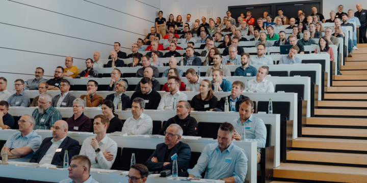 People in a modern lecture hall attentively follow a presentation.