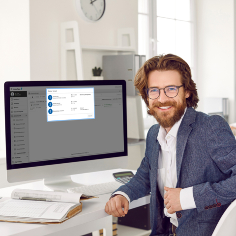 Lächelnder Mann am Schreibtisch mit Interflex eAU-Modul auf Monitorbildschirm