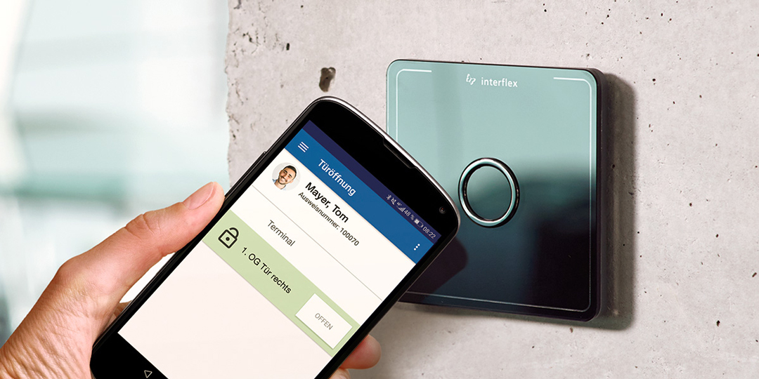 Smartphone mit Zutrittskontrolle-App auf dem Dispaly wird an Interflex-Zutrittsterminal IF-800 gehalten