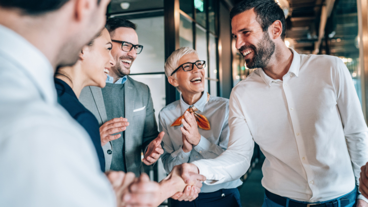 Groupe de personnes qui rient, deux personnes se serrant la main