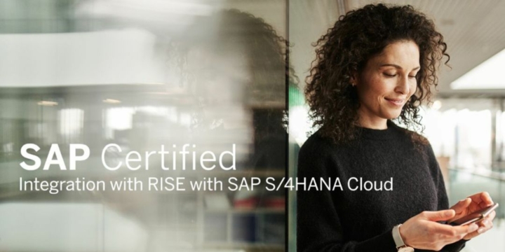 Frau lehnt an Glaswand im Bürogebäude und blickt lächelnd in ihr Smartphone