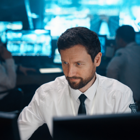 Mann im Sicherheitsleitstand blickt auf Bildschirmmonitor